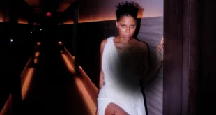 La artista dominicana Tokischa posando en Premio Lo Nuestro 2026 con un vestido blanco conceptual.