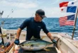 Pescador manipulando un ejemplar de atún aleta amarilla en alta mar