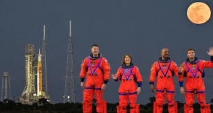Cohete SLS con la cápsula Orion en la plataforma de lanzamiento 39B y tripulación bajo la luz de la luna.