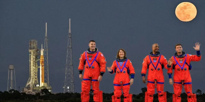 Cohete SLS con la cápsula Orion en la plataforma de lanzamiento 39B y tripulación bajo la luz de la luna.