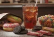 Un vaso de bebida azucarada junto a alimentos ultraprocesados altos en azúcar añadida.