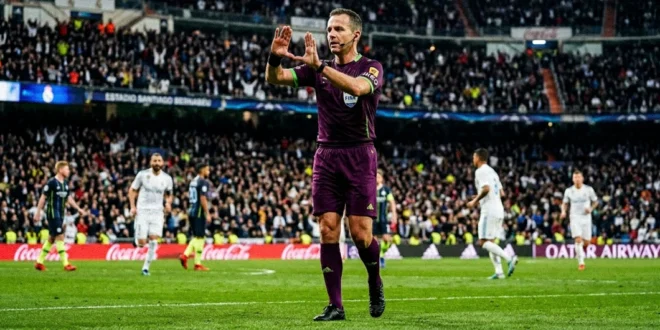 Árbitro de la FIFA señalando el VAR durante un partido de fútbol oficial