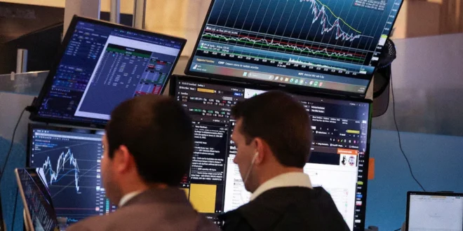 Operadores financieros analizando gráficos de cotizaciones de Wall Street en pantallas gigantes durante una sesión de alta volatilidad