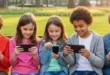 Niños sentados en un parque usando teléfonos móviles en lugar de jugar